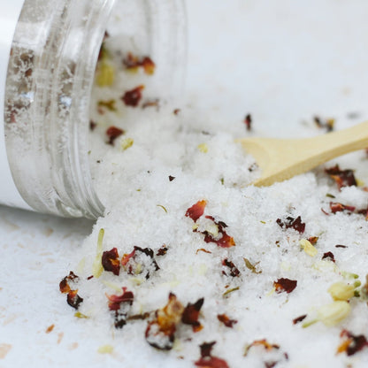 Close up photo of white bath salts with flower petals mixed in.