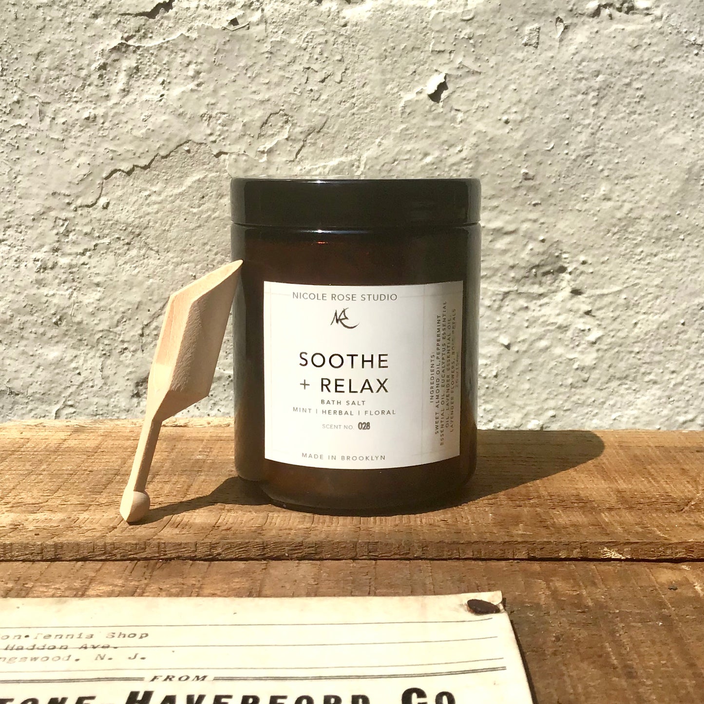 Straight on view of bath soak red-brown jar, with white label saying "Soothe + Relax"