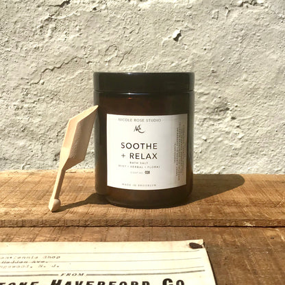 Straight on view of bath soak red-brown jar, with white label saying "Soothe + Relax"