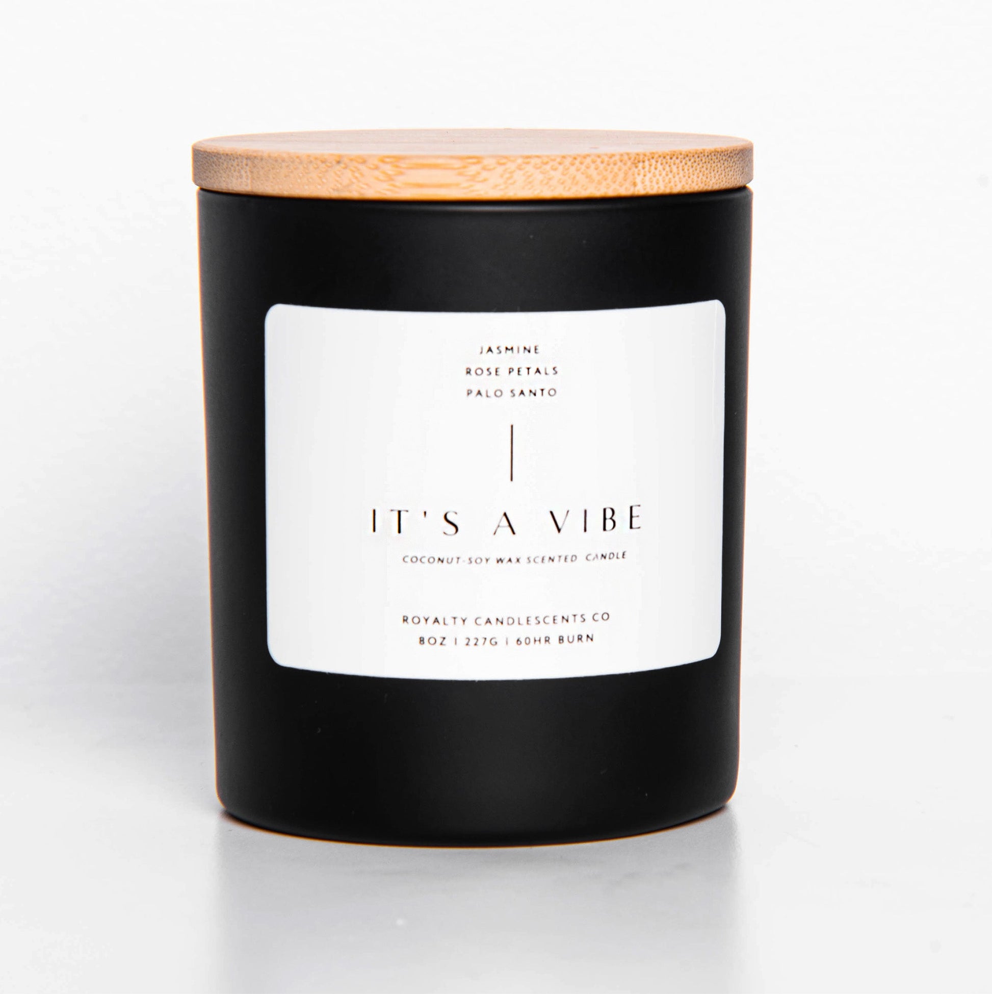 Black candle jar with wooden lid, with white label saying "It's A Vibe" in plain lettering.